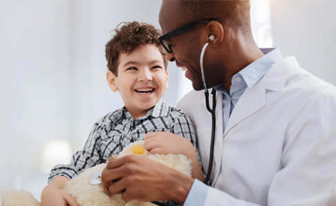 Doctor with stethoscope listening to a heart of a stuffed toy that is being held by a child