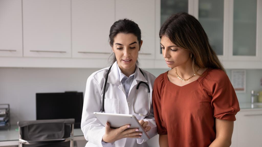 Optimistic Hispanic doctor woman showing medical report to female patient