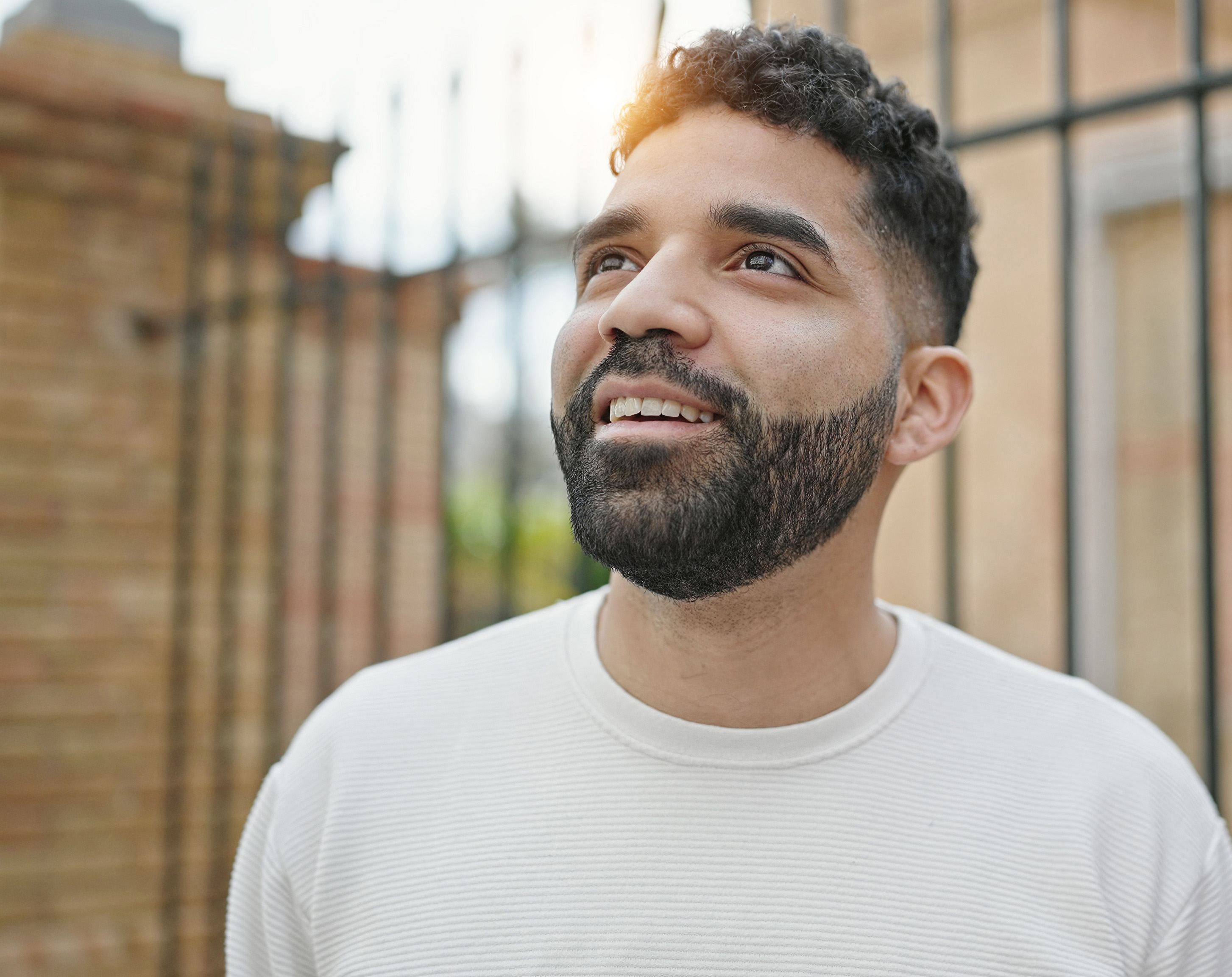 Young hispanic man smiling confident looking to the sky at street