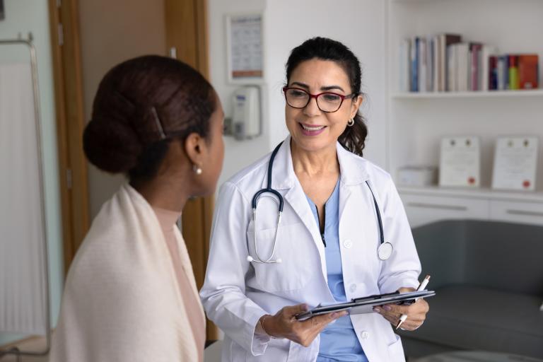 Cheerful senior doctor meeting with young African patient in clinic