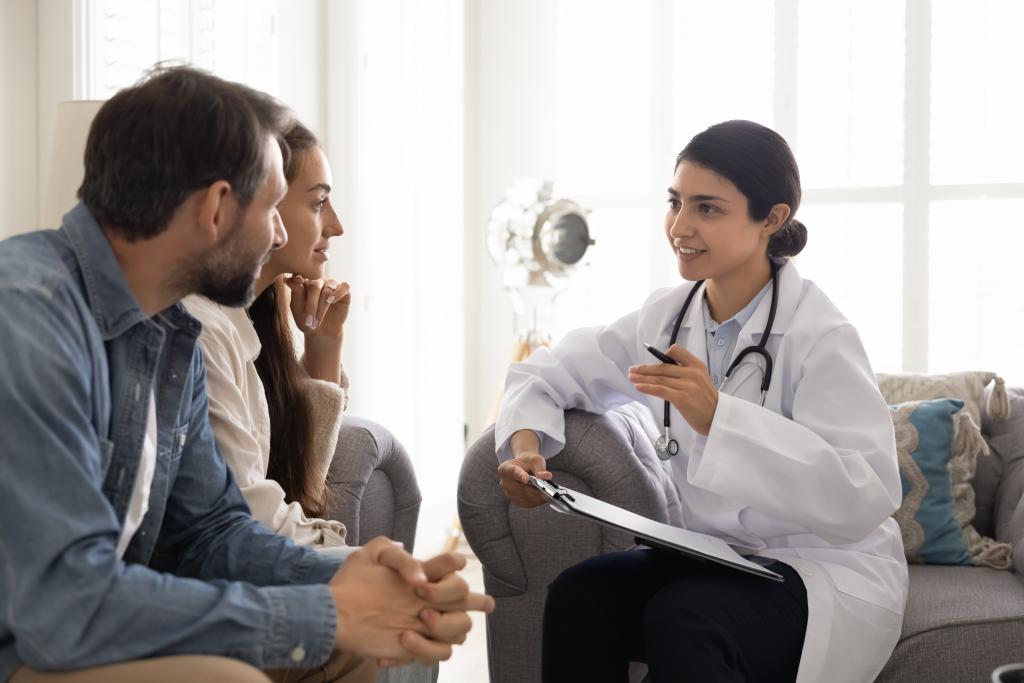 Positive young Indian doctor woman visiting couple at home