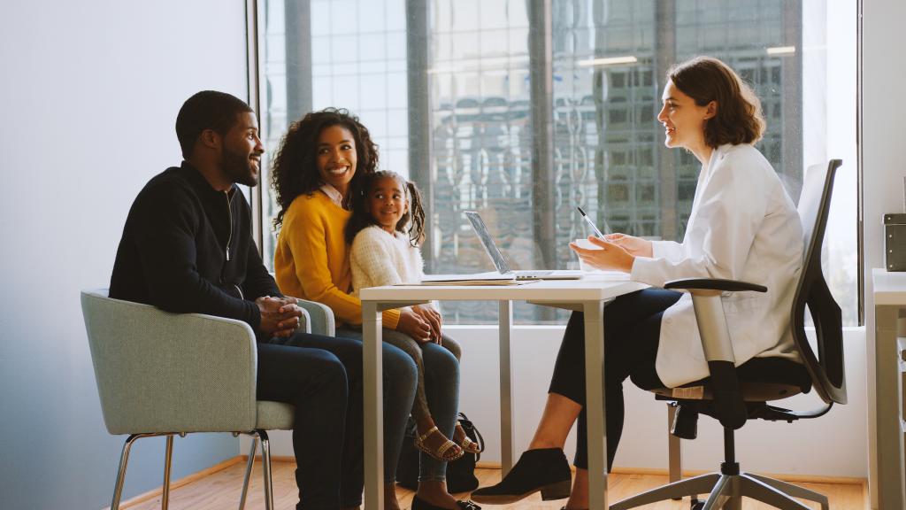 Family Having Consultation With Female Paediatrician In Hospital Office
