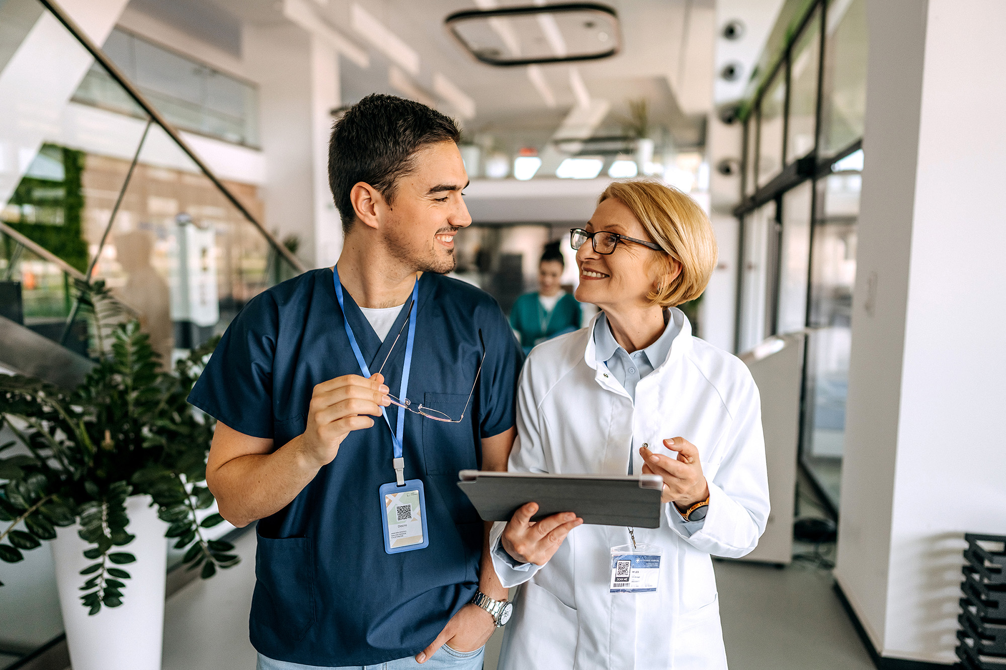 Senior female doctor talking to her young colleague in the hospital corridor
