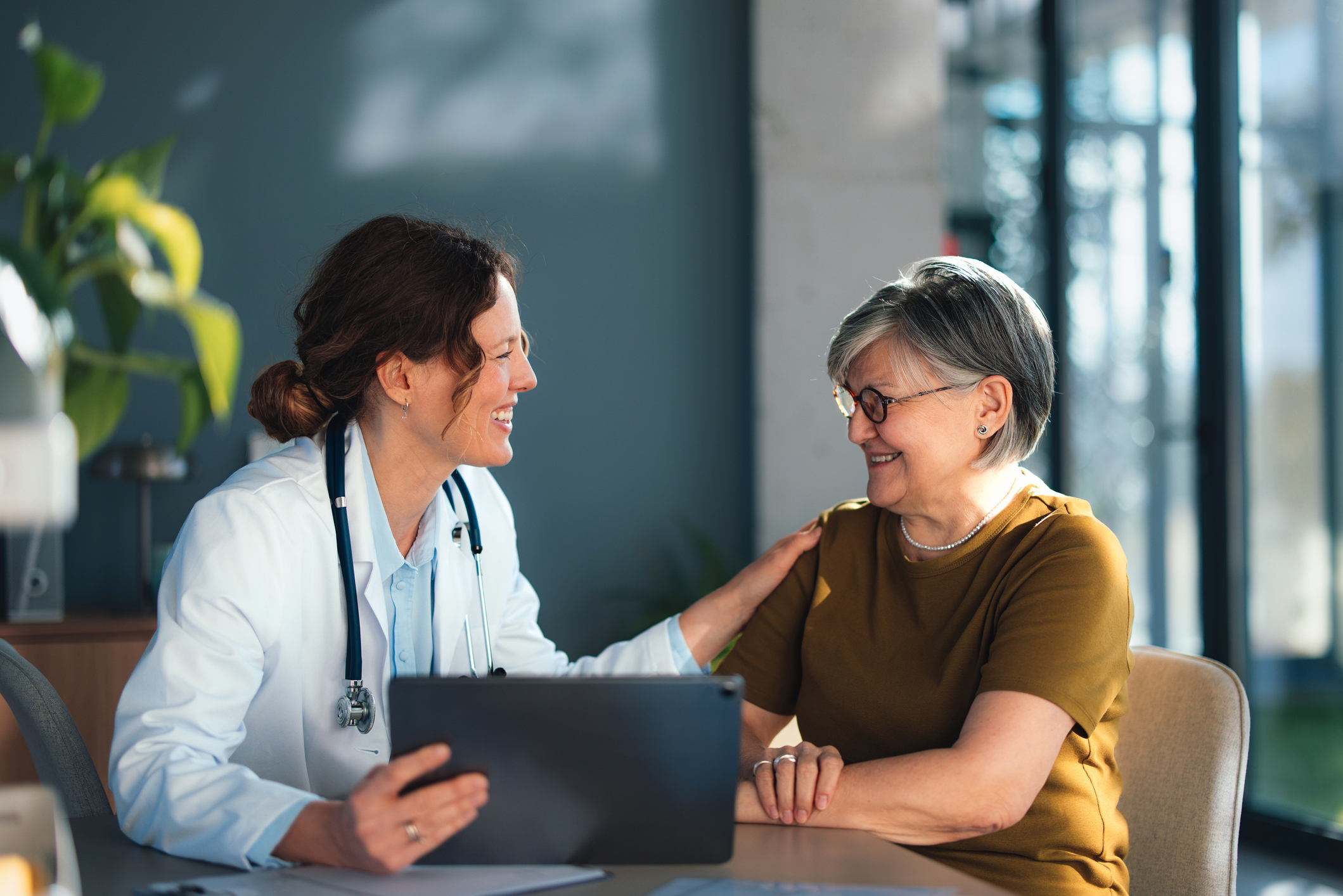 Doctor Consulting Senior Woman Patient in Bright Clinic Office Showing Trust and Compassion